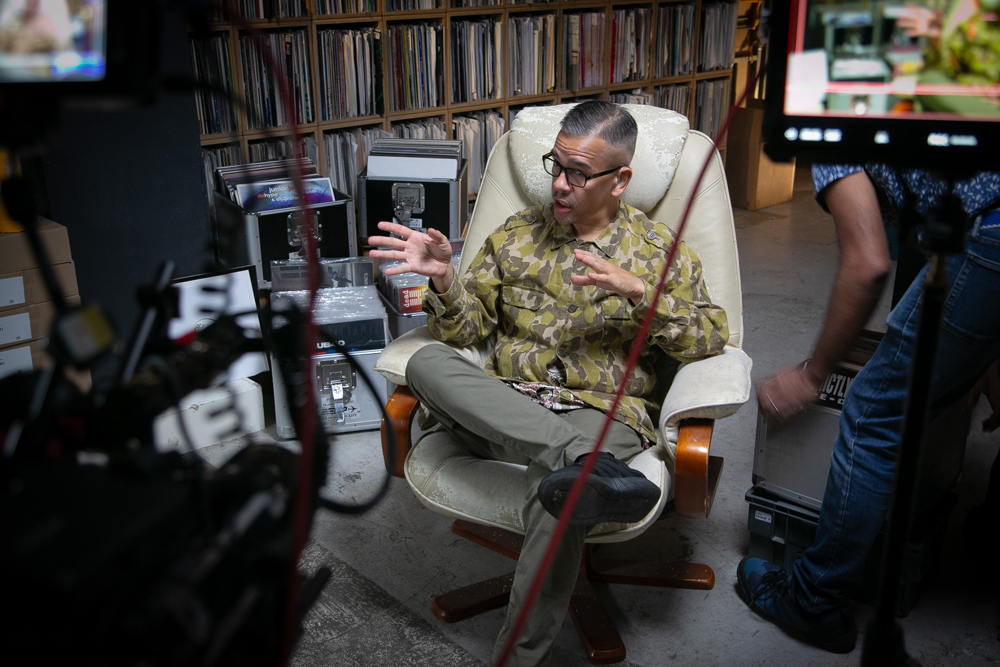 Troi lee sitting in an arm chair with filming equipment in shot